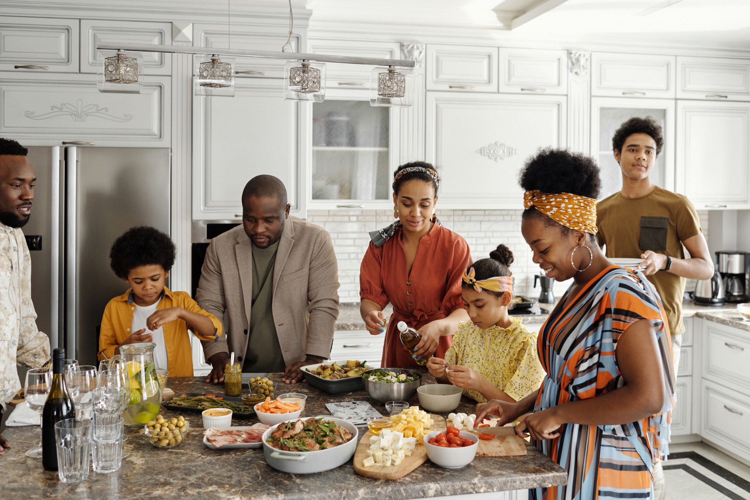 A Black family preparing a meal together in a bright kitchen.